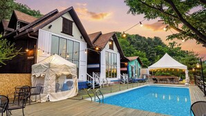 A pool area with a wooden deck, lounge chairs, and a tent. - Gapyeong Monami spa Pension (Gapyeong)