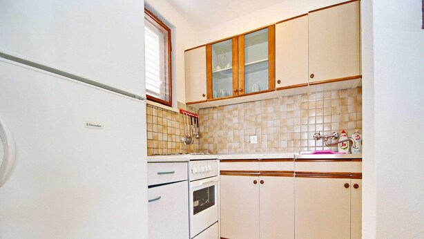 A kitchen with white cabinets, a white stove, and a tiled backsplash. - Oasis of Peace (Korcula)