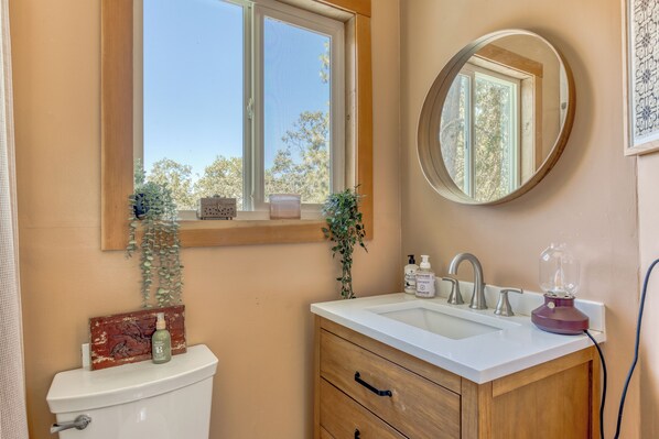A bathroom with a toilet, sink, vanity, and a window.