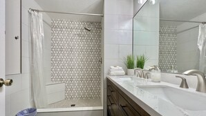 Ein modernes Badezimmer mit Dusche, Waschbecken und Spiegel.