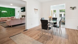 A modern living room with a green wall, a sofa, and a dining area with a glass table and chairs. - NEW! minutes to downtown - Private Half-Acre Ranch Retreat (Charlotte)