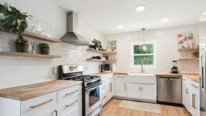 A modern kitchen with white cabinetry, a stainless steel stove, and wooden countertops. - NEW! minutes to downtown - Private Half-Acre Ranch Retreat (Charlotte)
