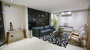 A modern living room with a grey sofa, a black and white rug, a coffee table, and a potted plant. - NEO PARK HOTEL (Maringá)