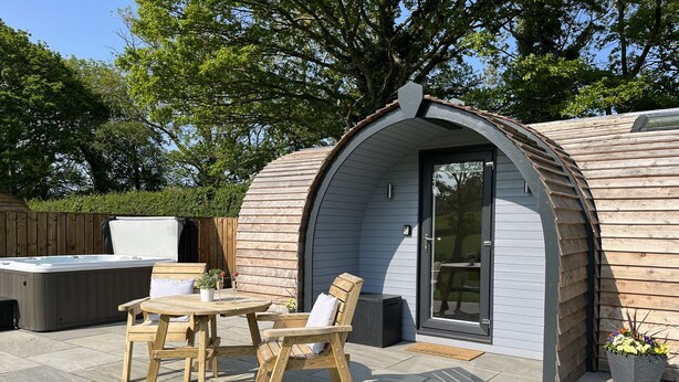 Un espace extérieur accueillant avec une table et des chaises en bois, un jacuzzi et une terrasse couverte.