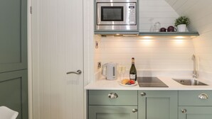 Une cuisine équipée d’un four à micro-ondes, d’un grille-pain, d’un évier et d’une bouteille de vin.