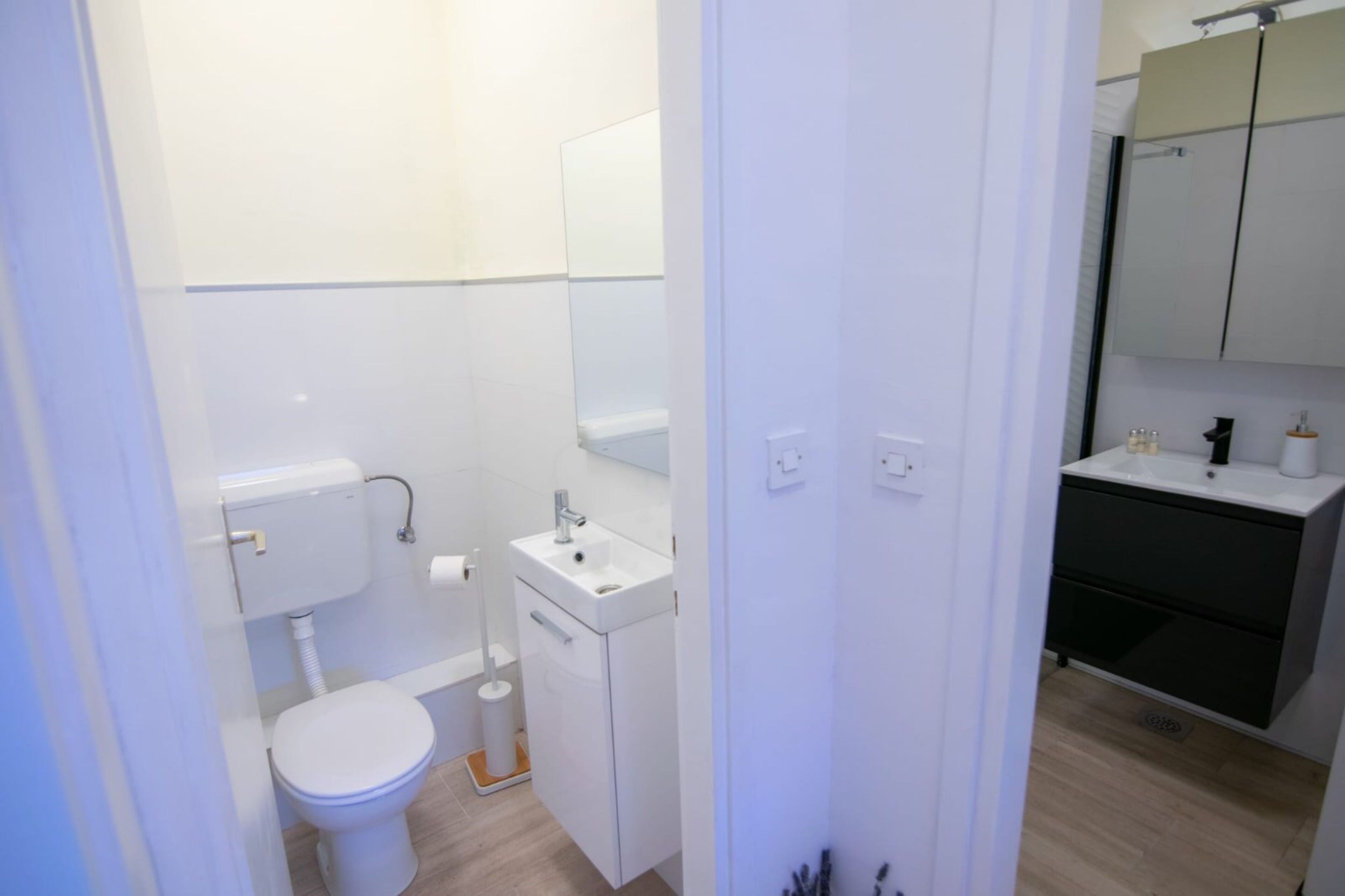 Une salle de bain moderne et compacte, équipée de toilettes, d’un lavabo et d’un miroir.