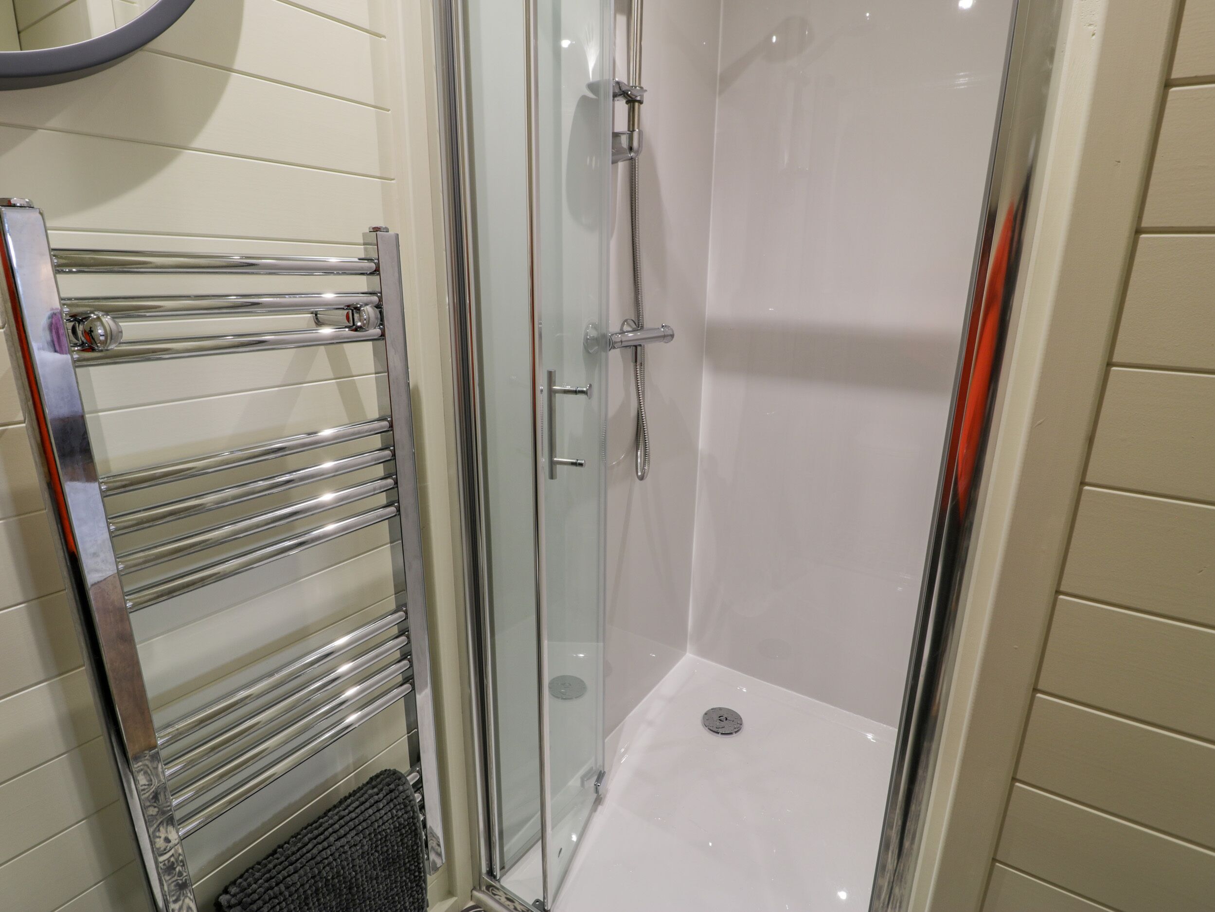 Un baño moderno con cabina de ducha de vidrio, toallero cromado y panel de control de la ducha.