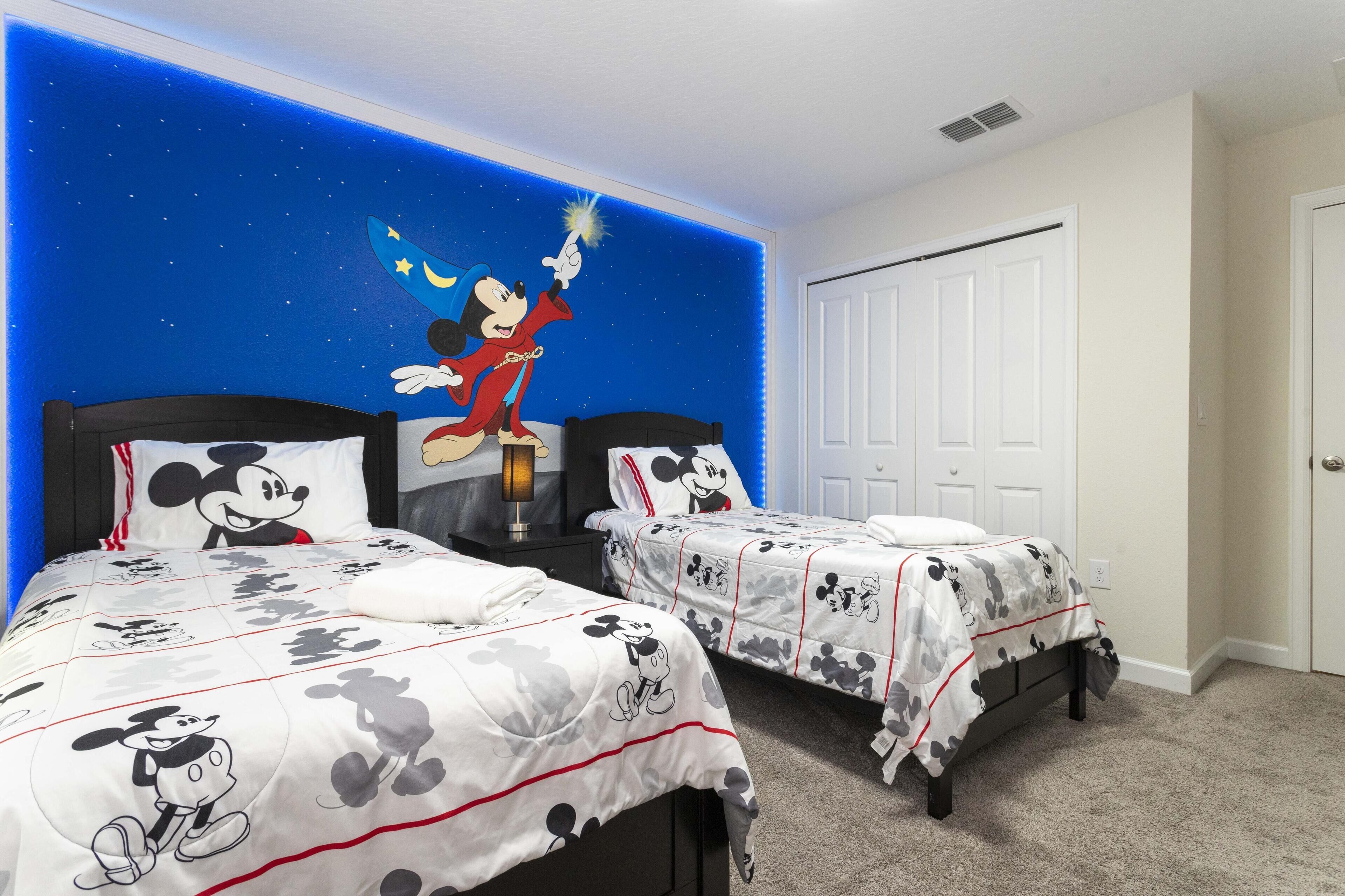 Une chambre avec deux lits, chacun agrémenté de linge de lit aux motifs de Mickey Mouse.