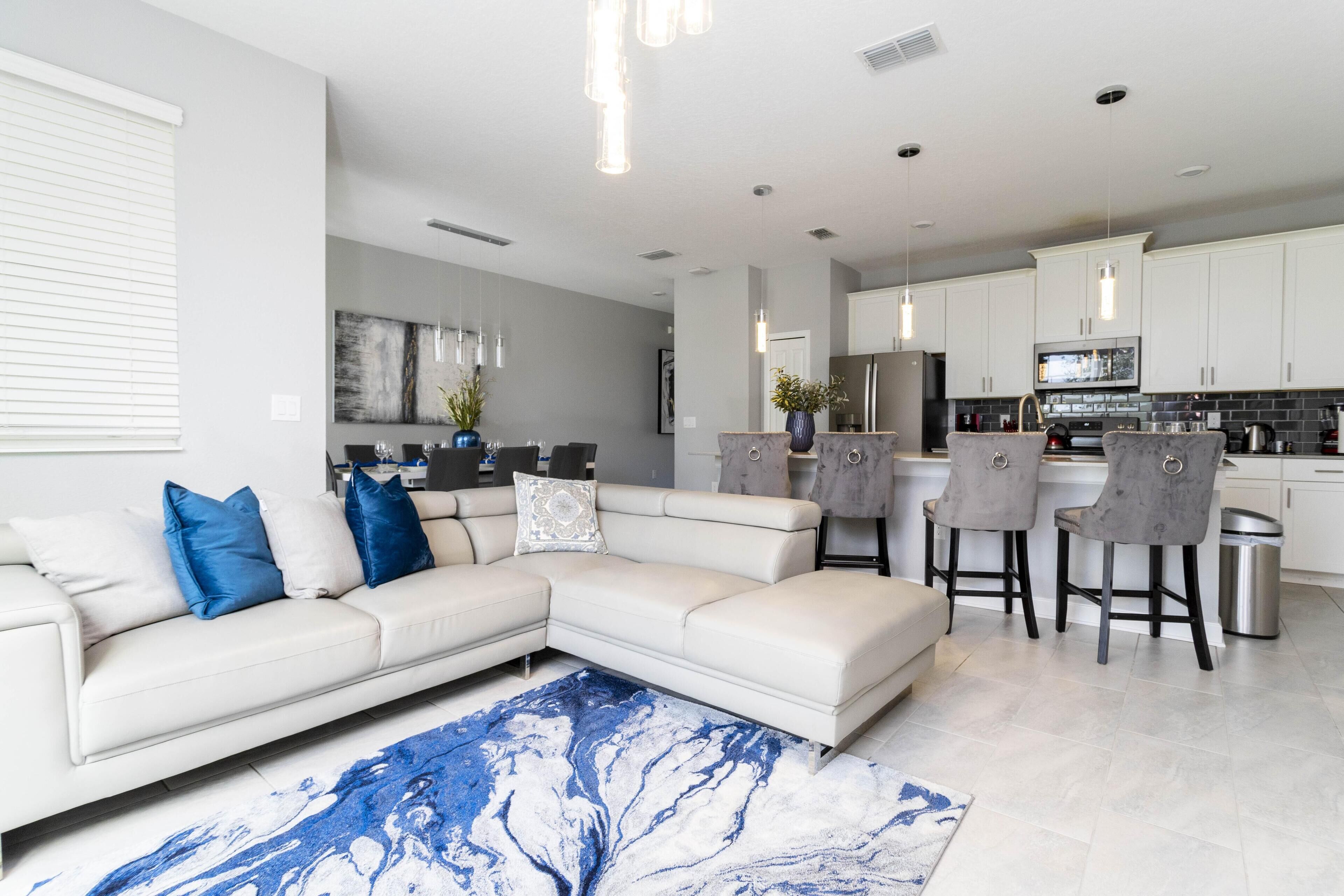 Un salon moderne avec un canapé d’angle, une table basse et un tapis en marbre bleu.