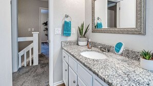 A bathroom with a granite countertop, two sinks, a large mirror, and a potted plant.