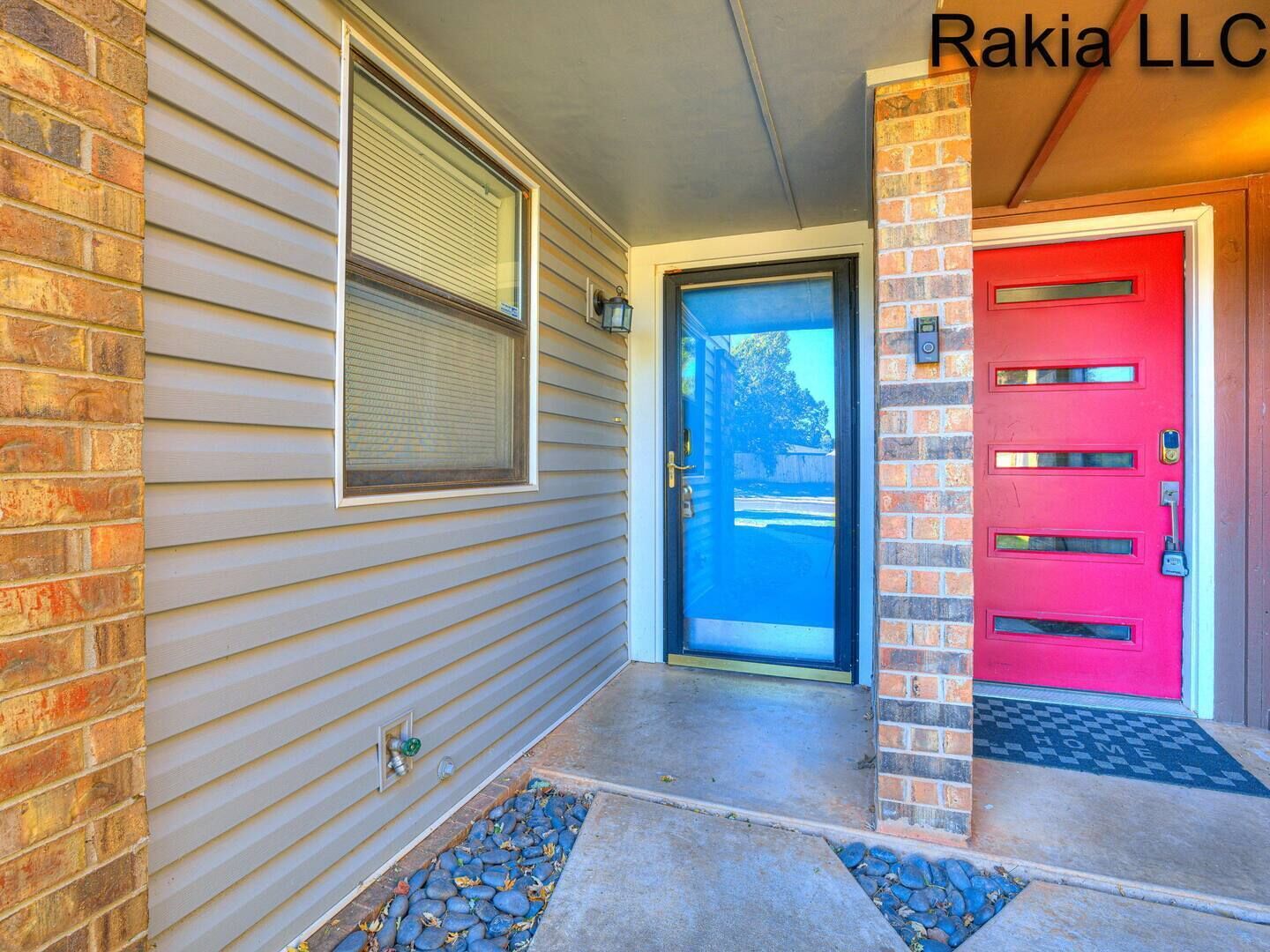 A house entrance with a red door, a window with blinds, and a mailbox.