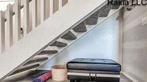 A staircase with a modern design, a cushioned bench, and a rolled-up mat on the floor.