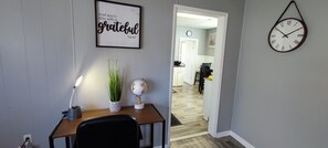 A home office with a desk, chair, lamp, potted plant, and a motivational quote on the wall.
