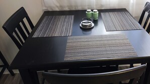 Una mesa de comedor con cuatro sillas negras, dos individuales y dos botellas de agua verdes.