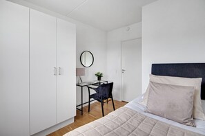 A bedroom with a bed, a desk, and a chair.