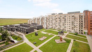 A residential building complex with multiple apartment buildings, a central courtyard with playgrounds, and a small bridge connecting different sections. - Modern Apartment Close to Royal Arena (Kastrup)