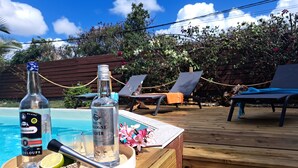 Een houten terras met een pooltafel, een fles rum en een glas water.