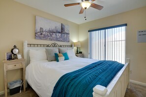 A bedroom with a bed, a nightstand, a wall clock, a framed picture, a window with blinds, and a ceiling fan. - 1 Mi to Surprise Stadium! Home w/ Patio & Hot Tub (Surprise)