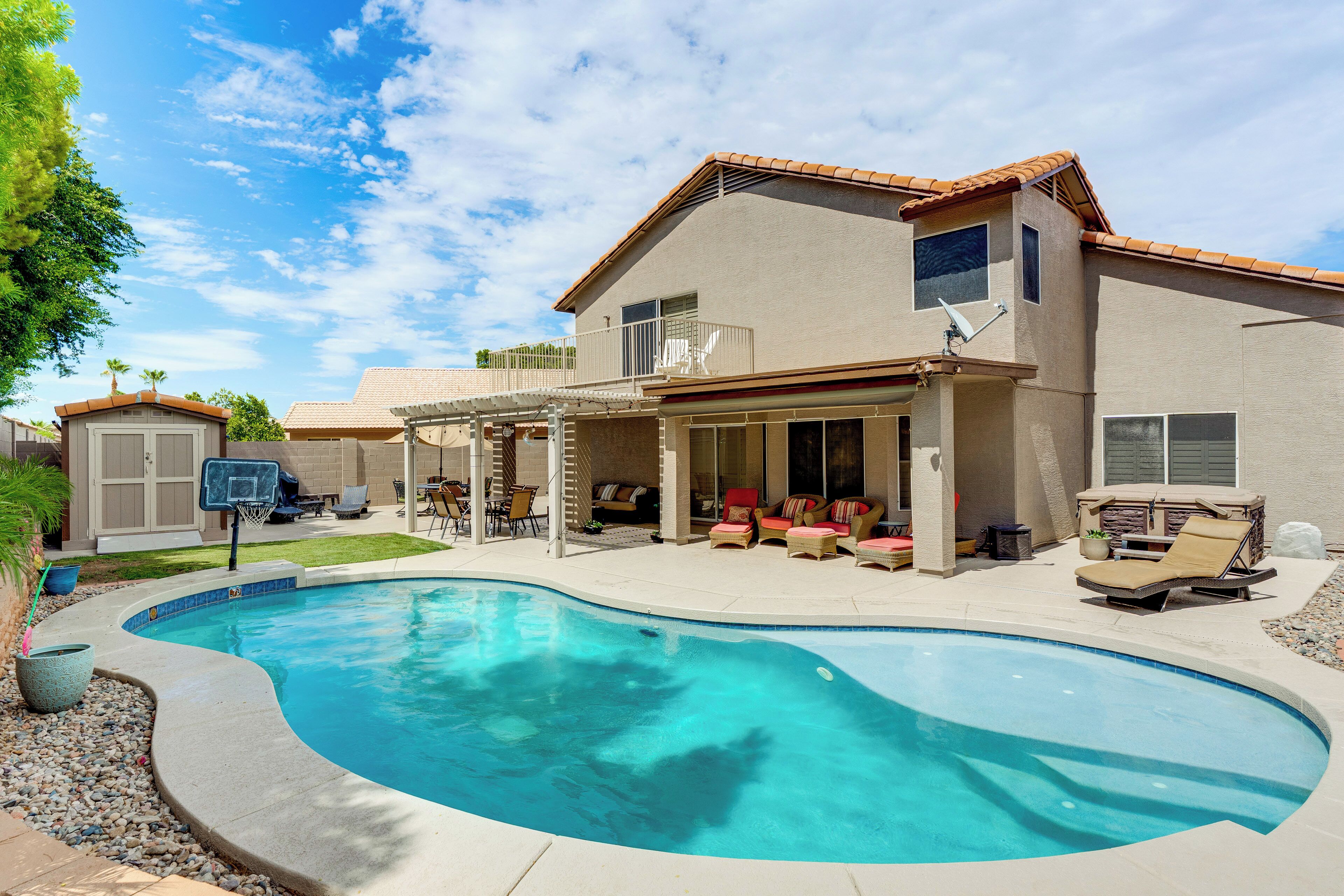 Une maison avec une piscine, du mobilier de jardin et un espace extérieur aménagé avec un coin salon couvert.