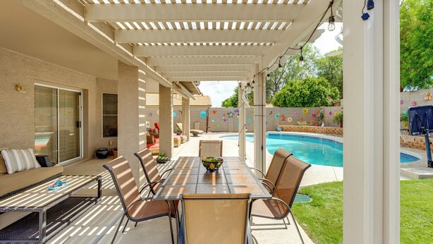 An outdoor patio with a table and chairs, a pool, and a covered area with a pergola. - 1 Mi to Surprise Stadium! Home w/ Patio & Hot Tub (Surprise)