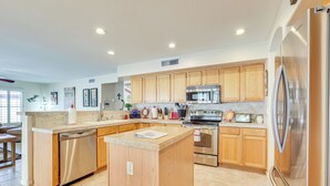 A modern kitchen with wooden cabinets, stainless steel appliances, and a central island. - 1 Mi to Surprise Stadium! Home w/ Patio & Hot Tub (Surprise)