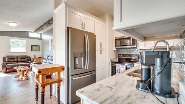 A modern kitchen with white cabinets, stainless steel appliances, and a marble countertop. - Private Dock: Waterfront Inverness Abode! (Inverness)
