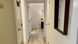 Een gang met houten vloer, witte muren en deuren die naar andere kamers leiden.