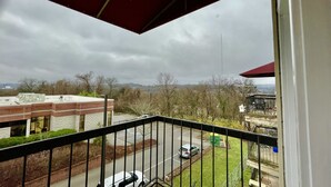 Een balkon met uitzicht op een parkeerplaats en gebouwen in de verte.