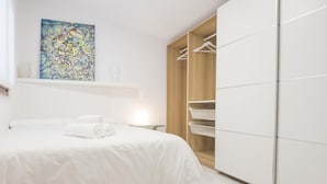 Une chambre moderne avec un grand lit, une armoire en bois et un tableau accroché au mur.