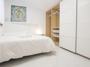 Een slaapkamer met een bed, een kledingkast en een schilderij aan de muur.