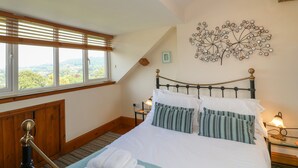 A bedroom with a bed, a window with blinds, a wall-mounted lamp, and a decorative tree artwork. - Longstone View (Bakewell)