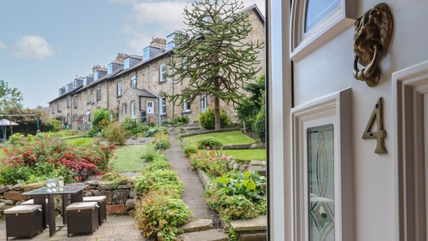 A garden view with a stone pathway leading to a seating area with outdoor furniture. - Longstone View (Bakewell)