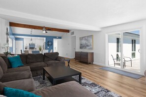 Relax in this spacious living room with a large sectional sofa, dining area, and sliding glass door leading to an outdoor patio.