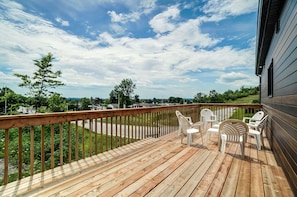 Una terraza de madera con mobiliario exterior y vista a una zona residencial.