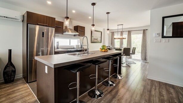 A modern kitchen with a central island, stainless steel appliances, pendant lighting, and a view to the dining area. - Peaceful House 10 minutes to ottawa and Excellent location (Gatineau)