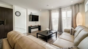 A modern living room with a sofa, a coffee table, a TV, and a console table with decorative items. - Peaceful House 10 minutes to ottawa and Excellent location (Gatineau)