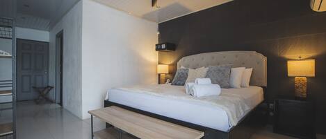 Un dormitorio moderno con una cama grande, un ventilador de techo, lámparas de noche y un banco.