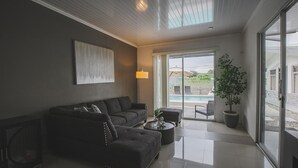 Un salon moderne avec un canapé, une table basse et une grande fenêtre donnant sur une piscine.