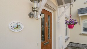 A house number plaque, a wooden door, and a hanging flower pot. - Rolo's Retreat (Grange-over-Sands)