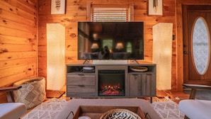 A cozy log cabin interior with a television, fireplace, and wooden walls.
