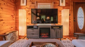 A cozy log cabin interior with a television, fireplace, and wooden walls.