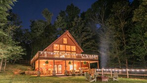 A log cabin with a balcony, outdoor seating, and a fire pit.