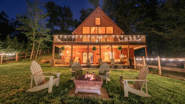 A wooden cabin with a balcony, outdoor seating, and a fire pit.