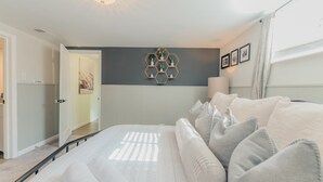 A bedroom with a bed, a wall-mounted hexagonal shelf with decorative items, a bedside lamp, and a door leading to another room. - Sloans Lake!  Walk to eateries/bars! Free parking! (Denver)