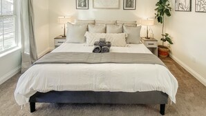 A neatly made bed with a grey blanket, two bedside lamps, and a potted plant on the right side. - Hot Tub, fully fenced, and dog friendly! (Indianapolis)