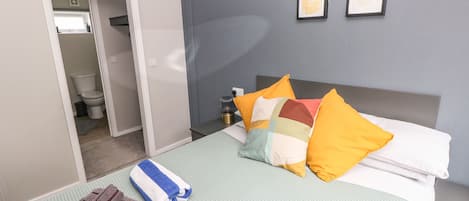 Ein Hotelzimmer mit einem Bett, Kissen, Handtüchern, einem Nachttisch und einem gerahmten Bild an der Wand.