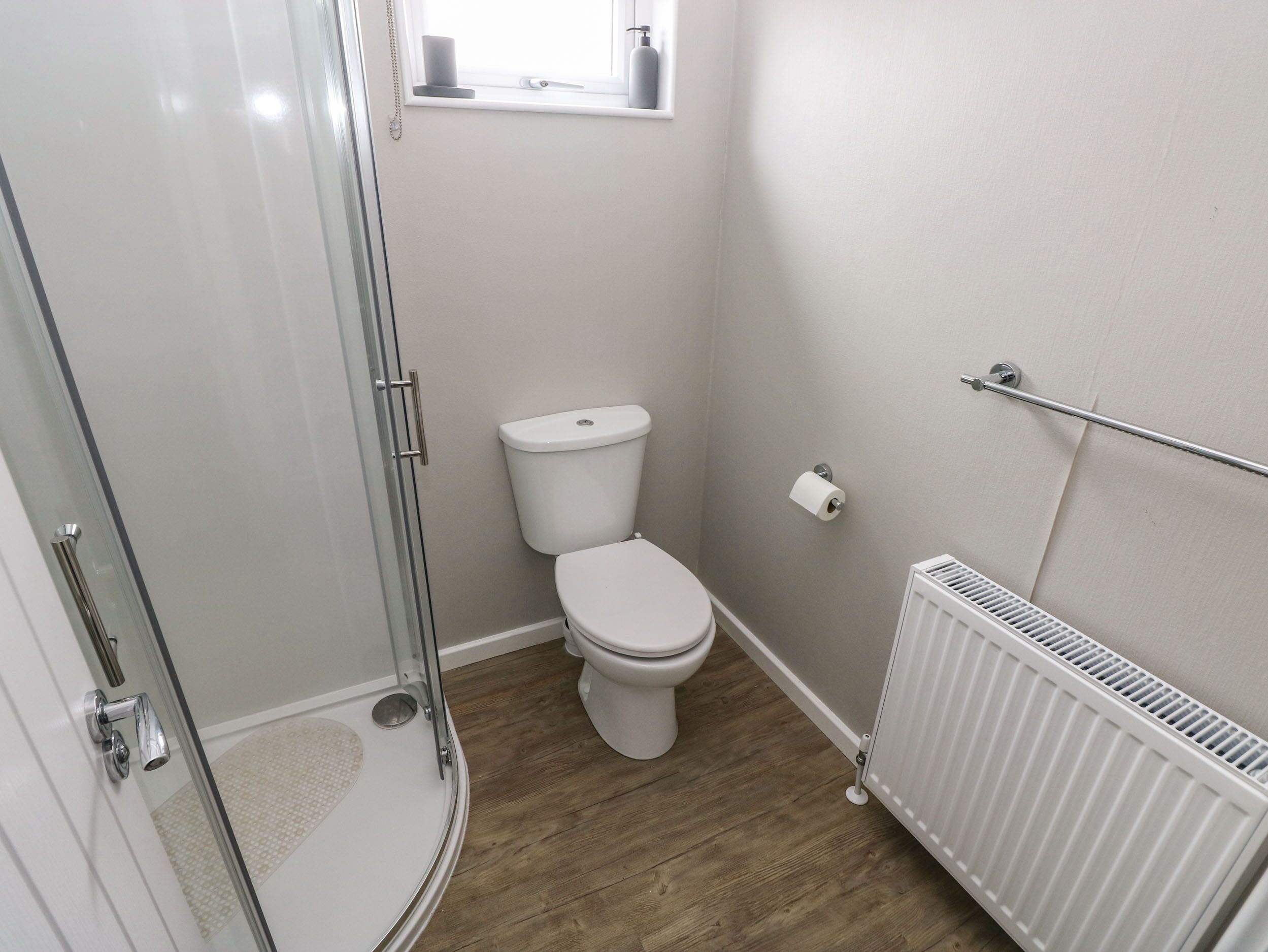 Une salle de bain avec une douche à paroi de verre, des toilettes et un radiateur.