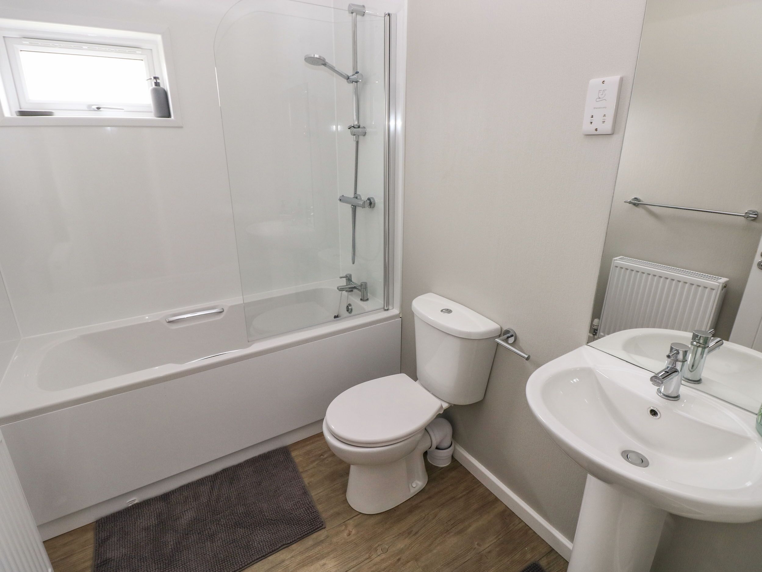 A modern bathroom with a glass-enclosed shower, a toilet, and a sink.