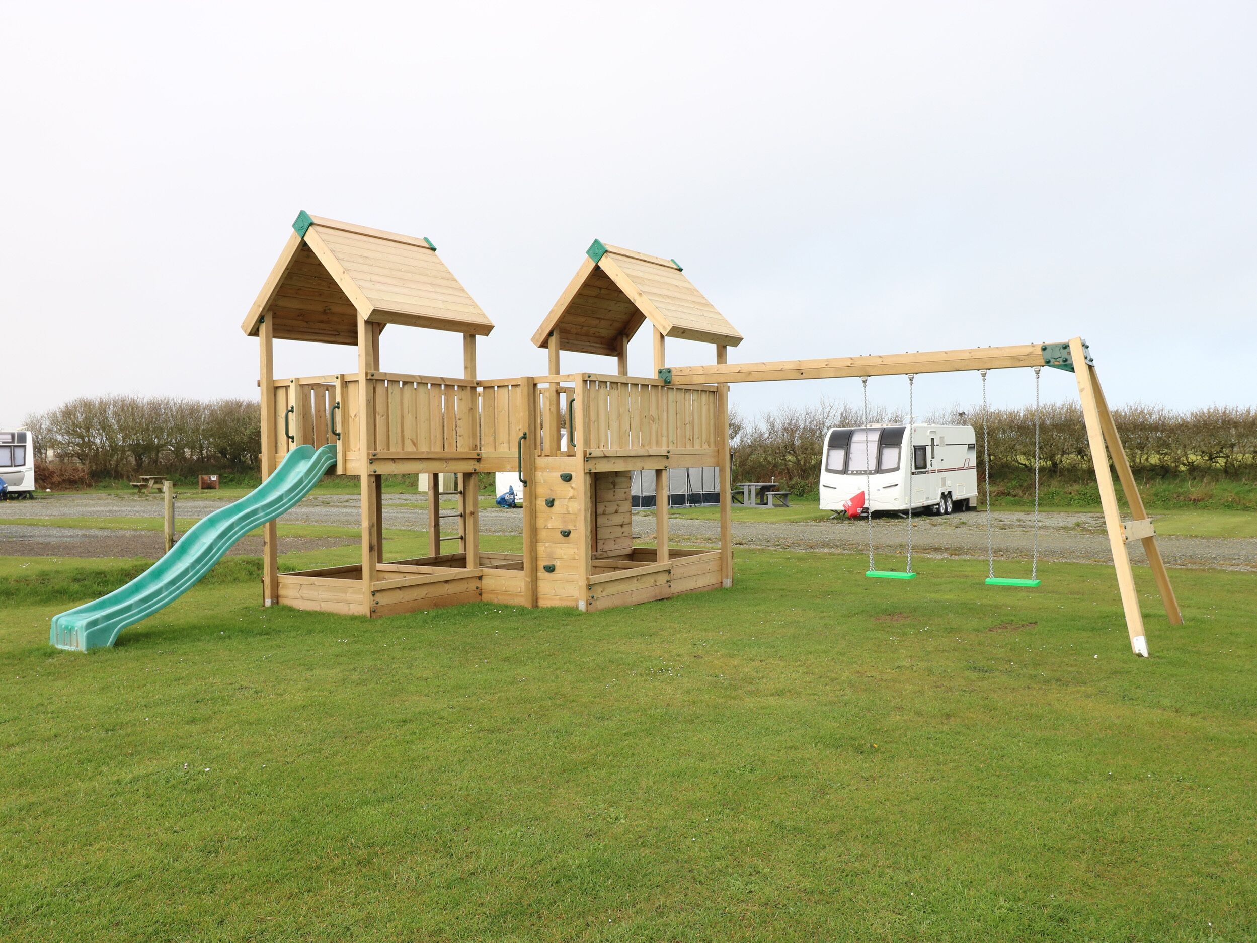 A wooden playground structure with a slide and swing set.