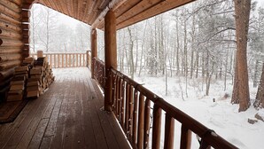 En træhytte med en overdækket veranda og udsigt til en sneklædt skov.